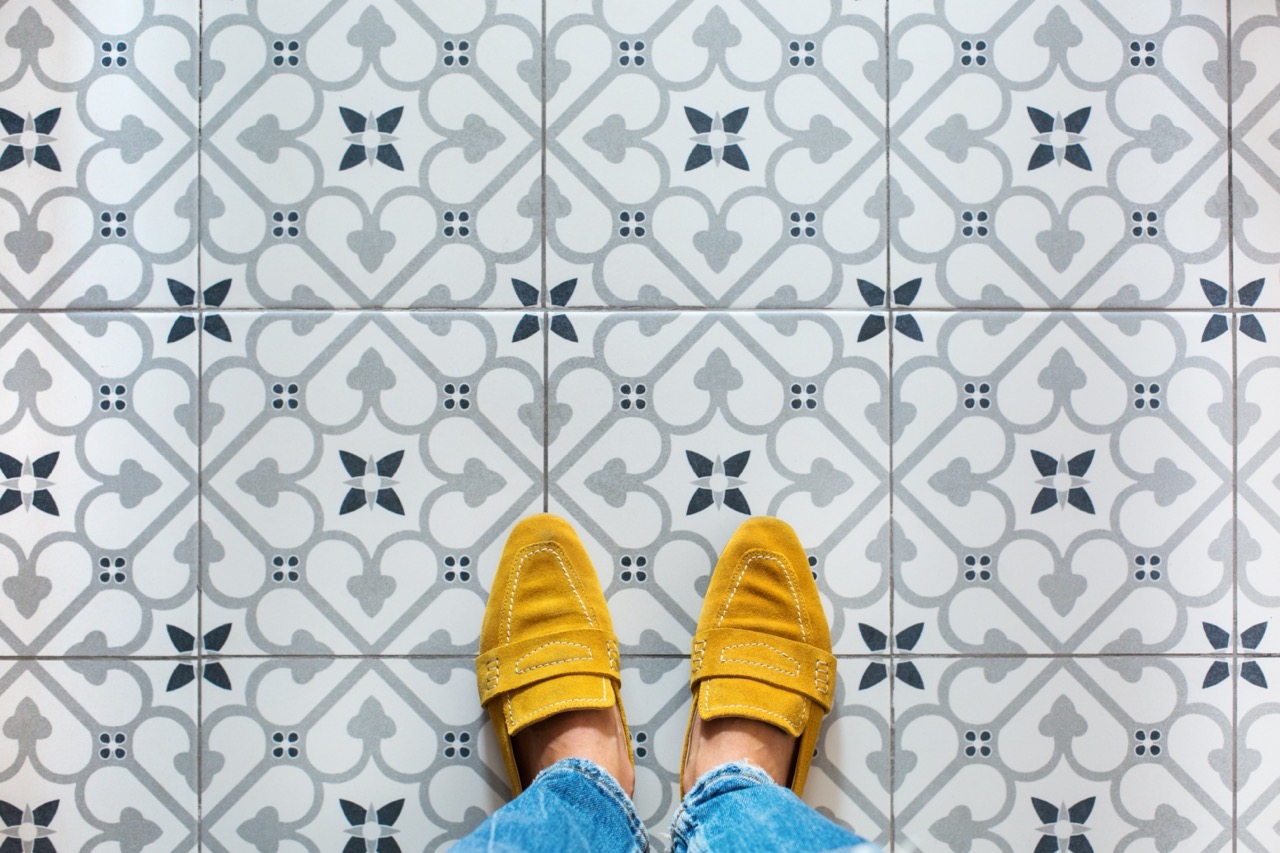 feet in yellow shoes on a mosaic tile floor.